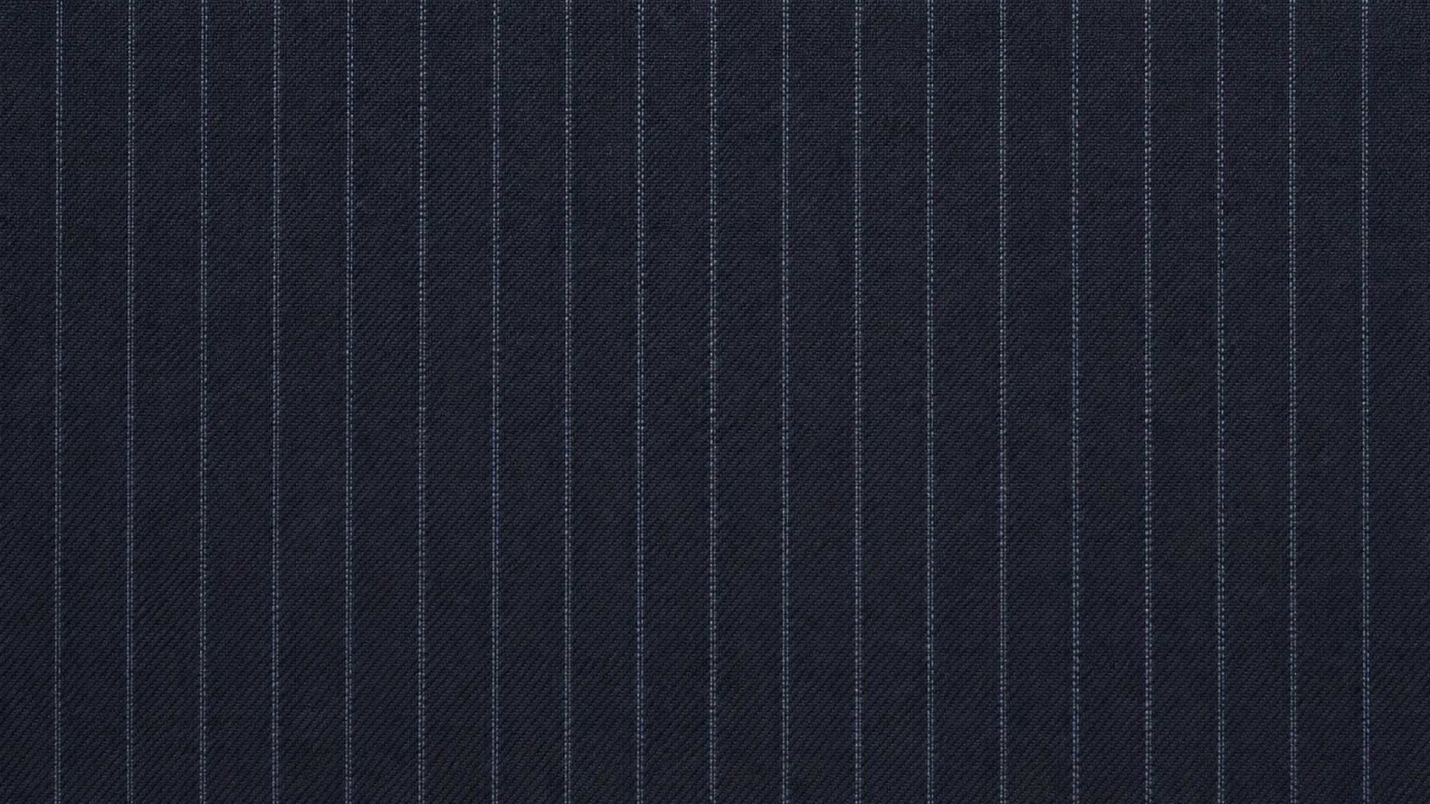 A length of navy pinstripe wool photographed flat and close: fine chalk stripes running vertically, evenly spaced, clean, with the twill of the weave visible between them.