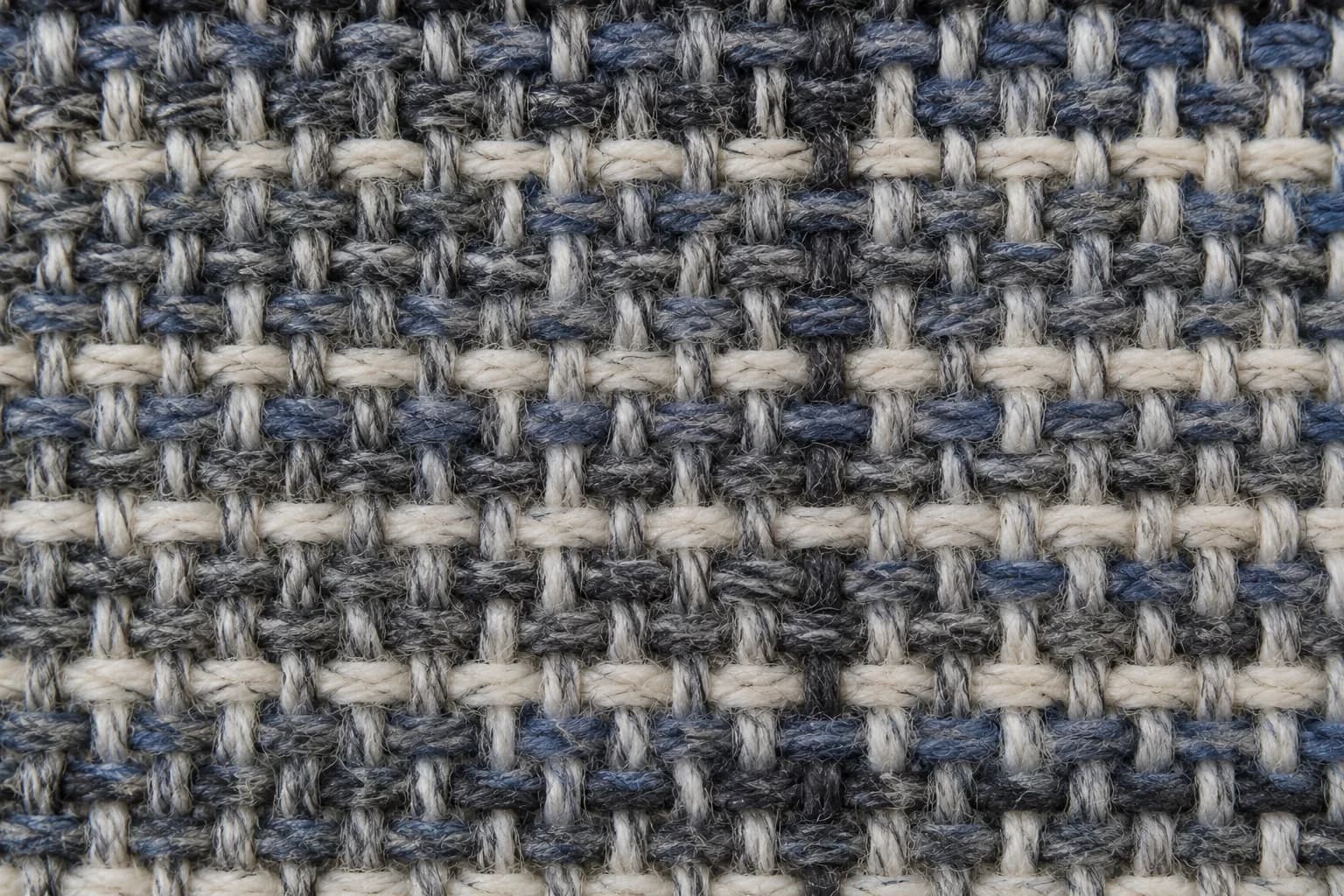 A woven cloth photographed close enough that individual warp and weft threads separate.