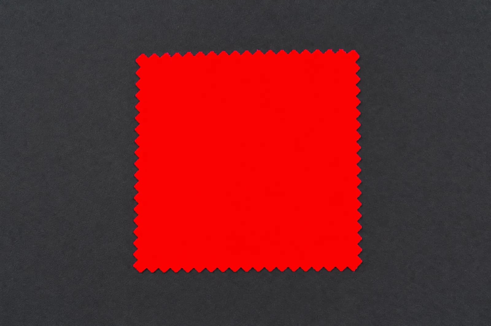 A swatch of saturated scarlet cloth flattened into a single glowing area with no weave visible inside it.