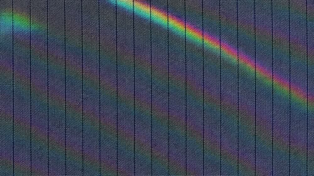Navy pinstripe wool filling a tall frame, with broad rainbow interference bands travelling steadily across it.